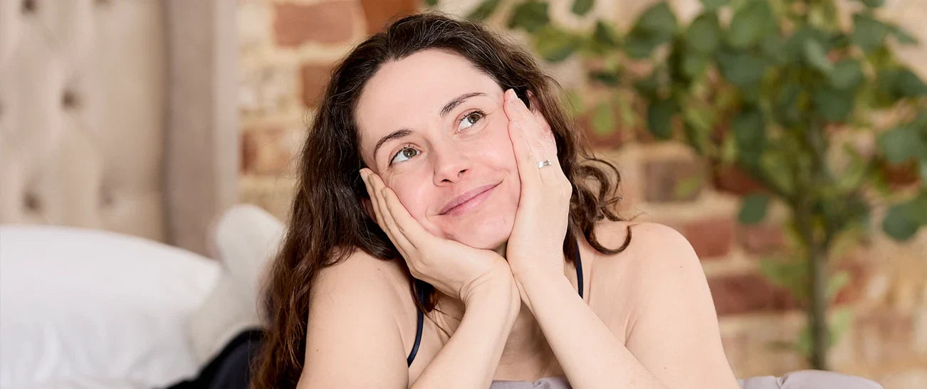 A lading on a bed holding her face.